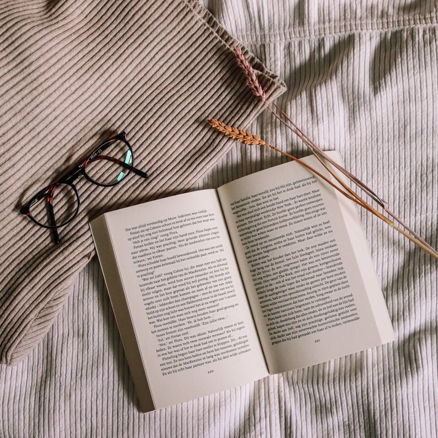 Locally authored book displayed on a bed with glasses